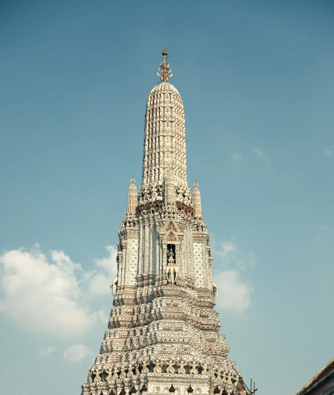 Le prang central du Wat Arun, à Bangkok, couvert de porcelaine, se détachant sur un ciel bleu.