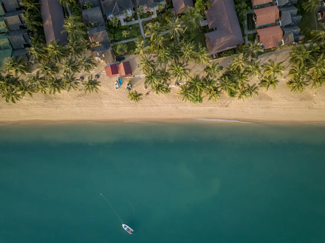 Vue aérienne de la plage de Maenam, à Koh Samui : sable bordé de cocotiers et eau turquoise.